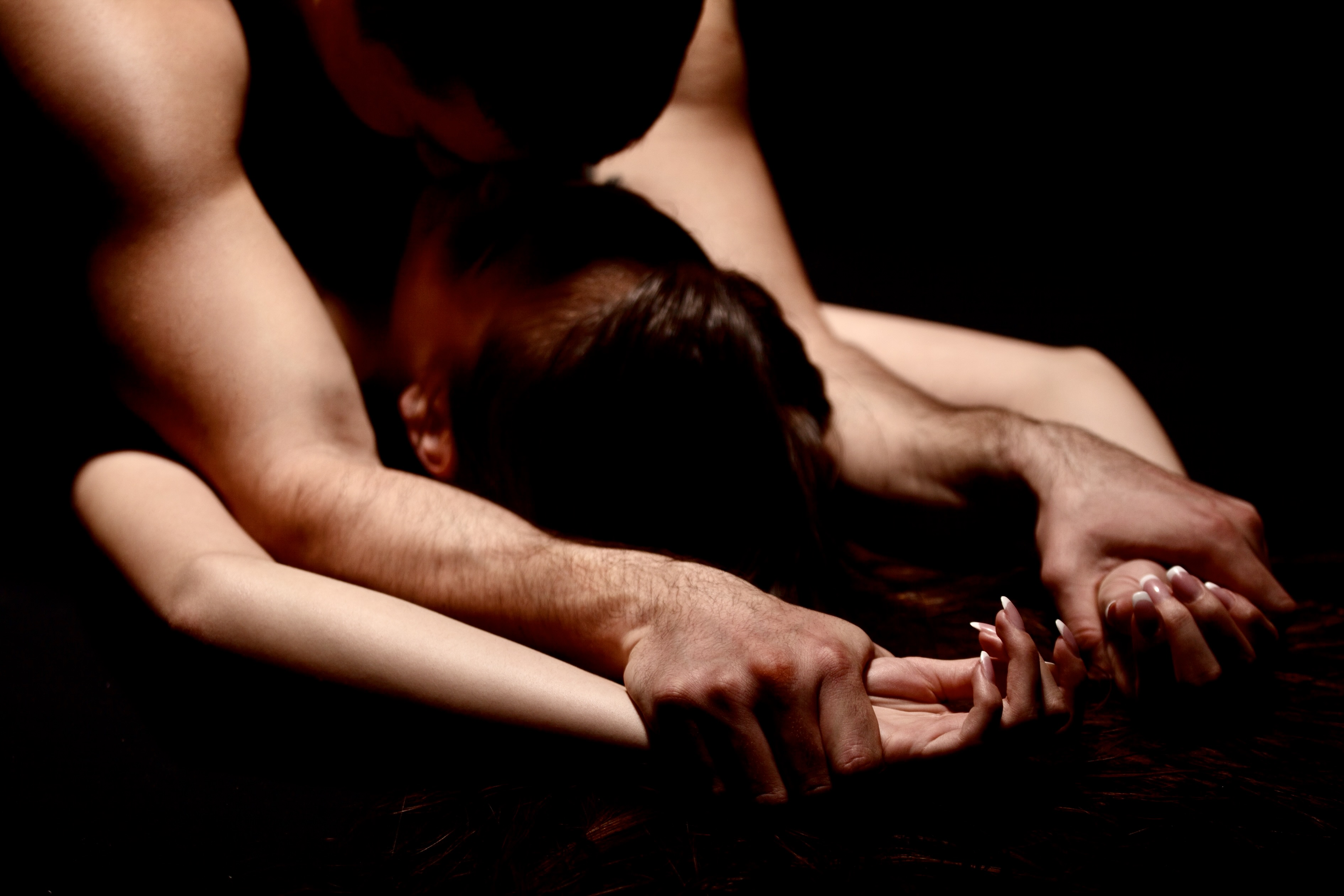 Yping cople have a sex with passion. Man is lying over woman and holding her hands.